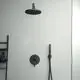 Schwarze Duscharmaturen von Ideal Standard an einer hellen Wand, mit einer Kopf- und Handbrause sowie einem Wandregal mit Pflegeprodukten.